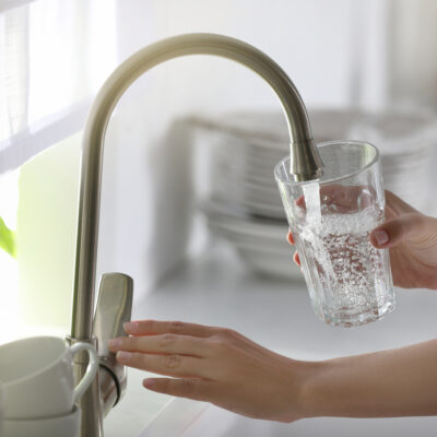 lady pouring water into a glass from her reverse osmosis water filter system