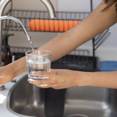 woman using a reverse osmosis water system to fill a glass of water