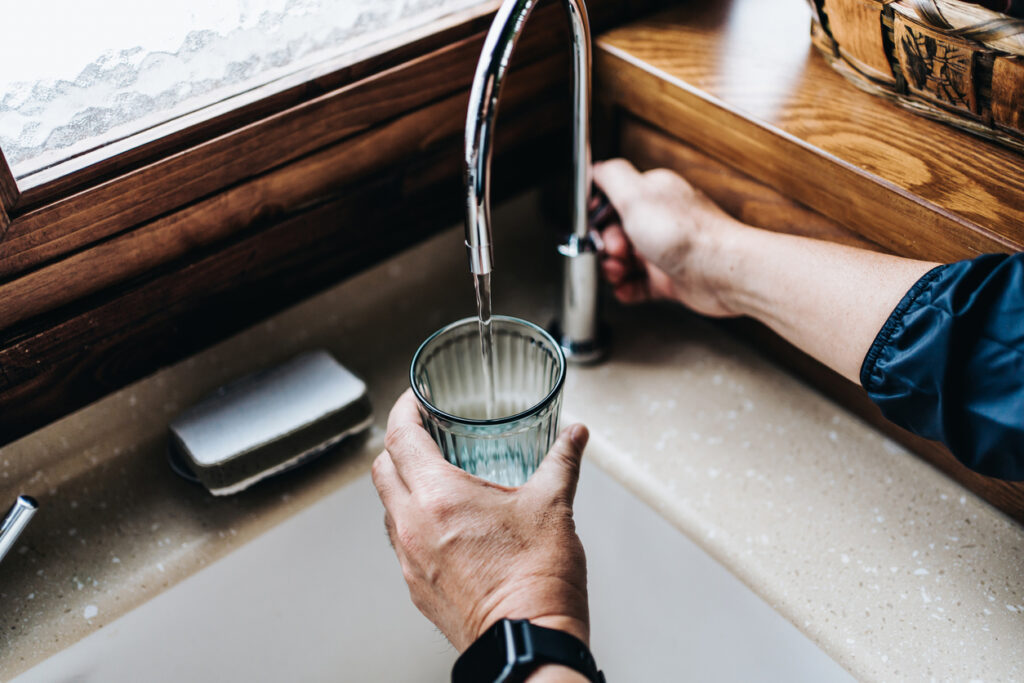 someone using a Reverse osmosis system to fill their drinking cup